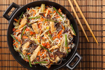 Rice noodles with chicken, mushrooms mun and vegetables in wook.