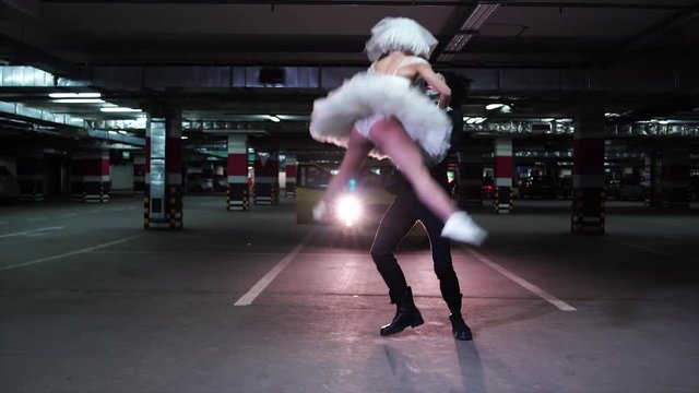 Young man in black suit dancing with freaky girl in the underground parking 4K