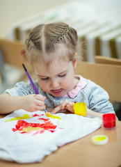 pretty little girl draws with paints, indoor