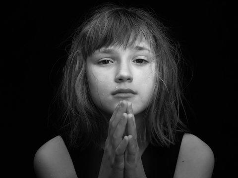 young girl crying. Hands in a gesture of prayer. Black and white portrait