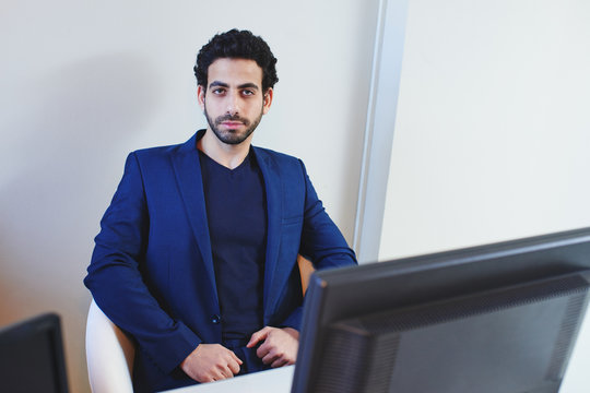 The portrait of Arab businessman in a jacket sits in the white chair in office