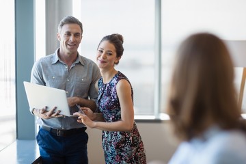 Fototapeta premium Smiling business colleagues discussing over laptop
