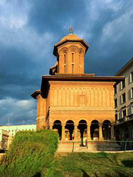 Exterior of historic Kretzulescu Church in Bucharest, Romania, in the sunset, with dramatic blue clouds in the background.