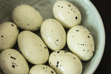 Chocolates in the form of quail eggs. Easter concept. Quail eggs in mint color plate. Close up, macro.