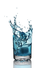 Splash in glass of blue alcoholic cocktail drink with ice cube