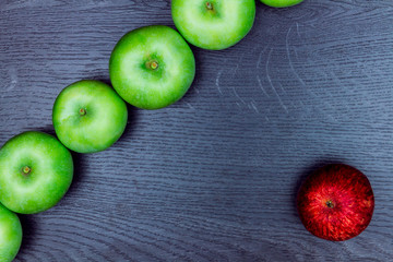 Healthy food. Red apple lying in front of the line made of green apples. 