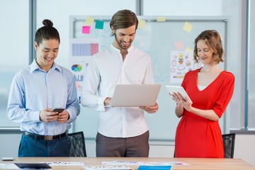 Smiling business colleagues using mobile phone