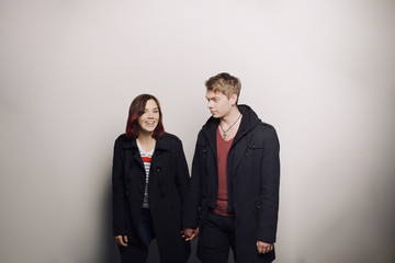 Happy young couple in winter clothes having fun in studio over white background