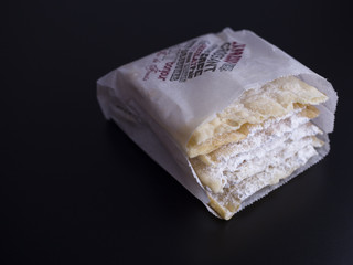 Oreillettes, french traditional pastry, sprinkled with powdered sugar and isolated on black background