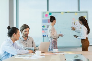 Fototapeta premium Business executives discussing over laptop in conference room