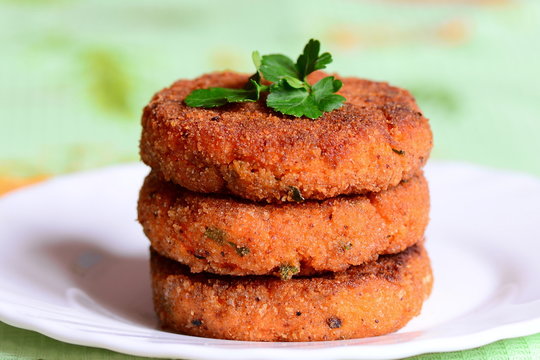 Veggie carrot cutlets on a plate. Tasty fried carrot cutlets with green onions and parsley. Healthy meatless food. Closeup