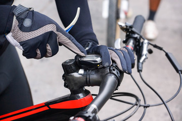 A mountain bike cyclist adjusting bike computer installed on a bicycle's handlebar