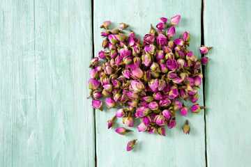 Fototapeta na wymiar dried rose buds on turquoise wooden surface