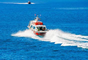 Red motor boats transfer people to Spetses island, Greece