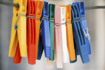 colored clothepins hanging on black rope on a blurred background , closeup capture
