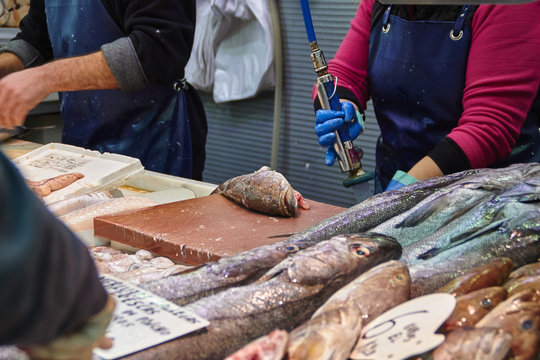 Vendor at Atarazanas market cleaning a fish