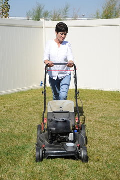 Mature female beauty mowing the lawn outside.