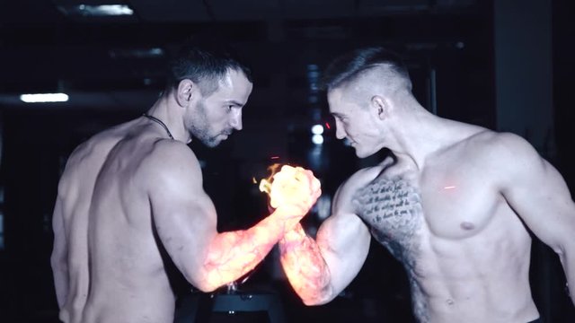 Two athletic fighters are fighting on his hands that light up with fire