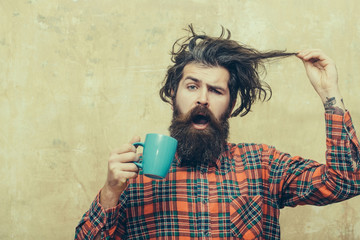 surprised bearded man pulling stylish fringe hair with blue cup