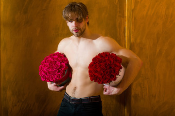 bearded muscular man with sexy body holds red rose box