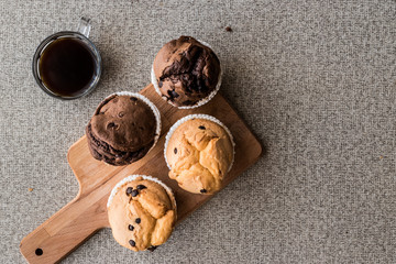 Chocolate and Vanilla Muffins with coffee on wooden surface.