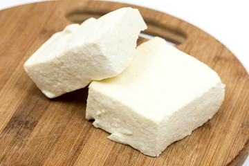 Fototapeta na wymiar Slices of white feta cheese on the wooden board
