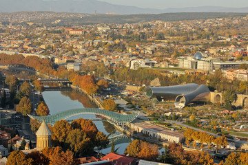 Autumn view to historical part of the capital of Republic of Georgia. In front two churchs Zion Cathedral then river Kura, Bridge of Peace, Europe square. Presidential Palace at the background. © Khrystyna Bohush