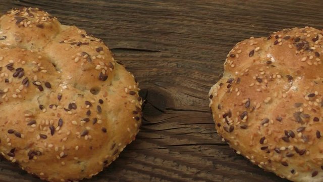 Fresh rye buns with sesame seeds on a wooden background
