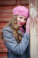Fototapeta premium Portrait of a girl in a pink beret and a gray-blue coat / The picture was taken in Russia, in the city of Orenburg, in a courtyard on Kobozev street