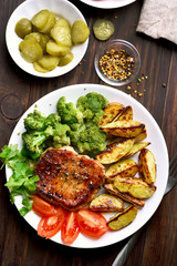 Grilled pork, potato wedges  and vegetable salad