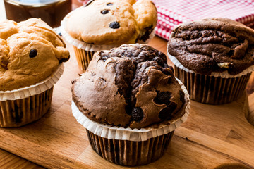 Chocolate and Vanilla Muffins with coffee on wooden surface.