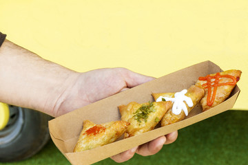 Details of a food truck, man's hand with food product, samosas