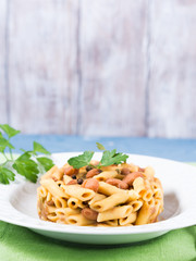 Served traditional Italian penne pasta with kidney beans on white plate and blue background