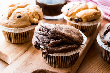 Chocolate and Vanilla Muffins with coffee on wooden surface.