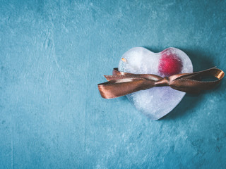 Heart shaped lavender syrup ice cubes with frozen cherry on blue textured background. Toned