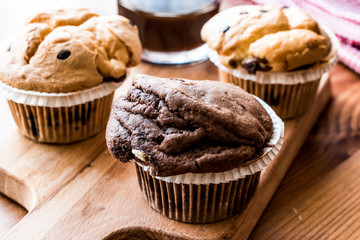 Chocolate and Vanilla Muffins with coffee on wooden surface.