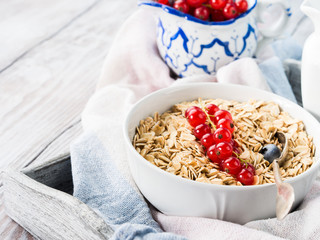 Bowl with raw oatmeal flakes rolled oats, milk and fresh berries on wooden background