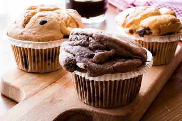 Chocolate and Vanilla Muffins with coffee on wooden surface.