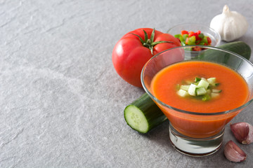 Traditional Spanish cold gazpacho soup and ingredients on gray stone
