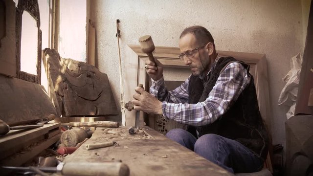 Wood carving. Carver with chisel and hammer. A skillful craftsman working on a panel of wood carve decoration