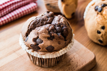 Chocolate and Vanilla Muffins on wooden surface.