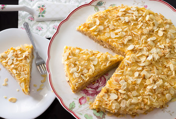 Homemade delicious cake with almond petals and cover custard or cream filling, on a support for the...