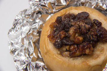 Yellow apple with walnuts, raisins and cinnamon, baked in foil on a white background