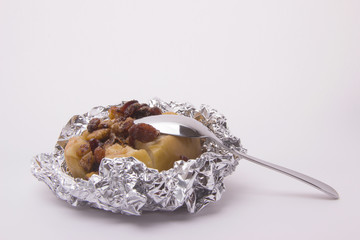 Yellow apple with walnuts, raisins and cinnamon, baked in foil on a white background