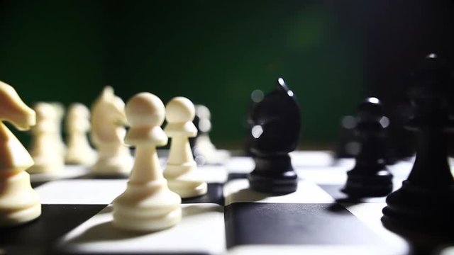 Still shot of the white and black pieces on a chess board, with shallow depth of field and focus transition.