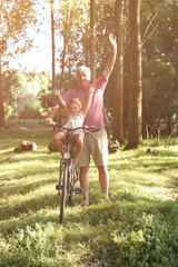 Senior man with granddaughter in bicycle basket.