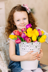 Obraz na płótnie Canvas Portrait of litlle girl holding tulips bouquet