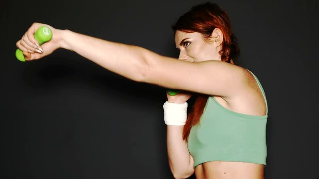 
Young  attractive sports woman box with  dumbbells in front of dark background
