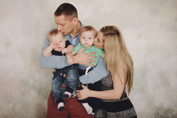 Happy family portrair,mother and father kissing two sons. Parents with baby two boys twins. 