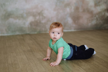 One year old cute baby boy sitting on wooden floor 